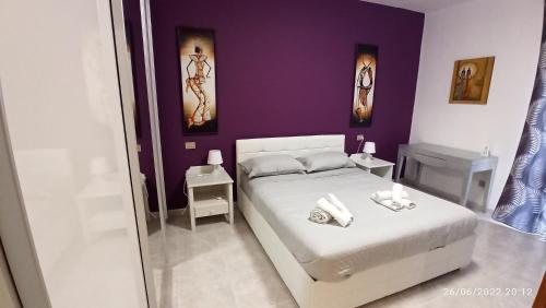 a bedroom with a white bed and purple walls at Mare e Città in Selargius