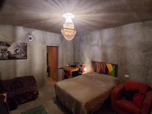 a bedroom with a bed and a chandelier and a chair at La Casa del Naufrago in Lobitos