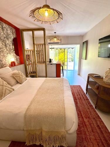 a bedroom with a large white bed and a kitchen at Studio Le Cosy Jungle & Piscine in Pointe-à-Pitre