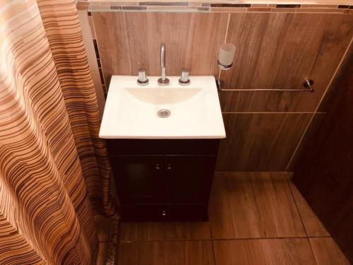 a bathroom with a white sink and wooden walls at Complejo Renacer in Villa Parque Siquiman