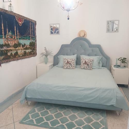 a bedroom with a bed with a blue headboard at Sultana in Ech Chorfa
