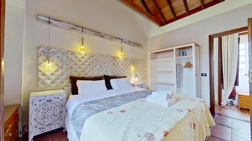 a bedroom with a large bed with white sheets at Finca Paraiso Casa Rural Tenerife Ecoturismo in Las Lagunas