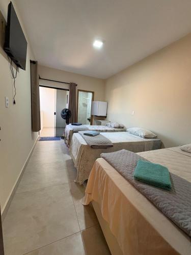 a room with three beds and a flat screen tv at Pousada Nascer da Lua in São Thomé das Letras