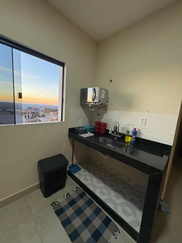 a kitchen with a counter with a sink and a window at Pousada Nascer da Lua in São Thomé das Letras