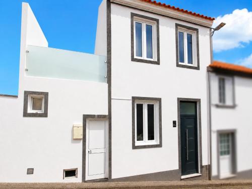 a white house with two doors and a red roof at Faial Inn in Horta