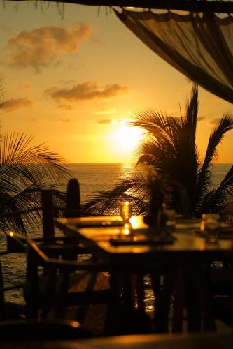a sunset on the beach with a table and chairs at La Joya Sayulita in Sayulita