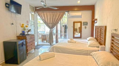 a hotel room with two beds and a television at Casa ka'an in Isla Mujeres