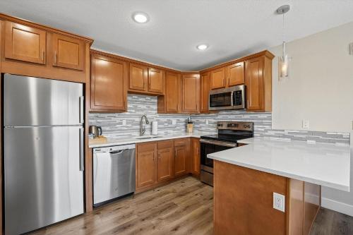 a kitchen with wooden cabinets and a stainless steel refrigerator at Kasa LoHi Denver in Denver