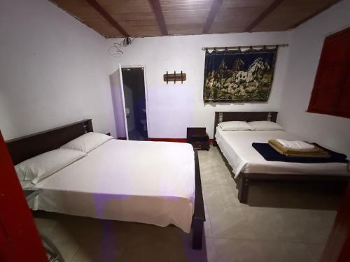a bedroom with two beds and a painting on the wall at Paisa Territory Lodge in Jardin