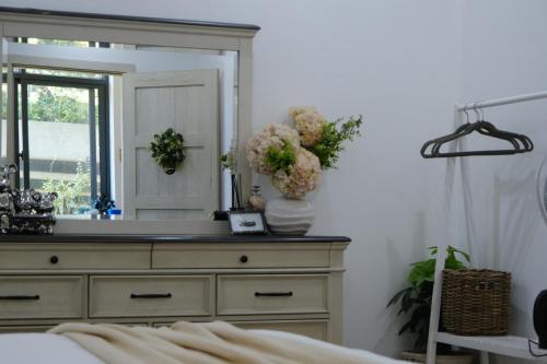 a bedroom with a dresser with a mirror and flowers at Cloudy Homestay Hoi An in Hoi An