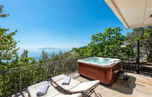 a hot tub on a balcony with two chairs at Pet Friendly Apartment In Matulji in Matulji
