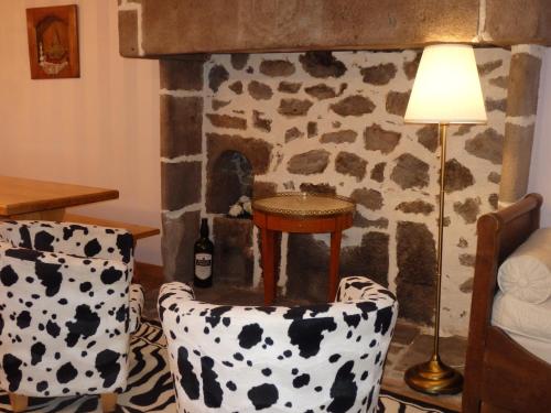 - un salon avec une cheminée en pierre, des chaises et une lampe dans l'établissement La Maison De Béatrice, à Murat