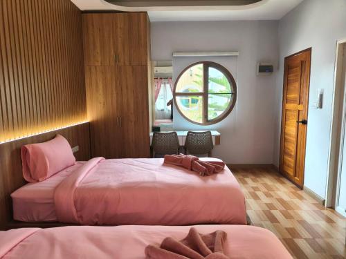a bedroom with two beds and a window at นนท์ ณ in Ban Non Makhuk