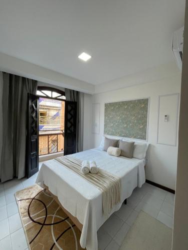 a bedroom with a white bed with towels on it at Hotel Brisa Serrana no Centro de Serrinha in Serrinha
