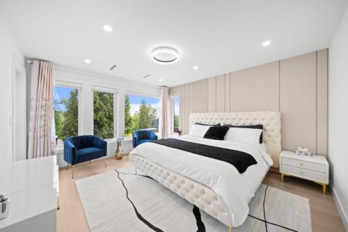 a white bedroom with a large white bed and windows at North Shore Luxe Villa in North Vancouver
