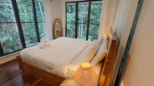 a bed in a room with windows in a bedroom at Rainforest Escape moments from Waterfall in Kuranda