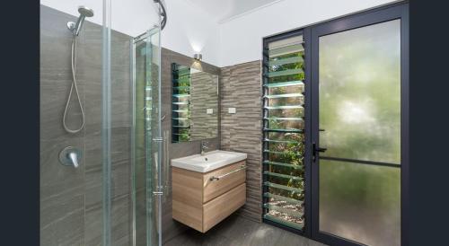 a bathroom with a sink and a glass shower at Rainforest Escape moments from Waterfall in Kuranda