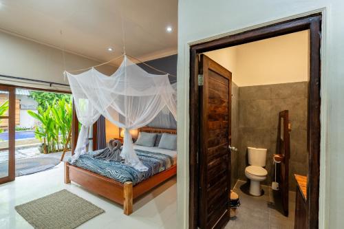 a bedroom with a canopy bed and a toilet at Divine Divers Gili Meno in Gili Meno