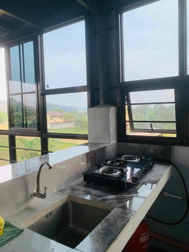 a kitchen with a stove and a sink with windows at ASHBURN'S TRANSIENT LA UNION - BAUANG, Self Service, Self Check-in, MOTORCYCLE Parking in Bauang