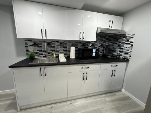 a kitchen with white cabinets and a sink at Spacious Entire Basement Suite with Free Parking Self Check In in Winnipeg