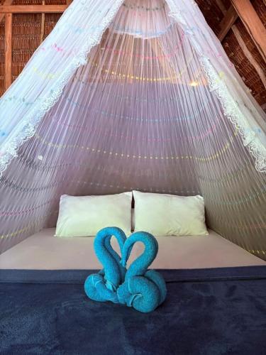 two blue towels sitting on a bed in a tent at Warahnus dive homestay in Kri