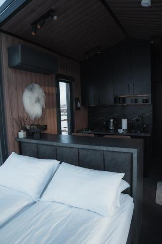 a bedroom with a bed with white pillows and a kitchen at Tiny Glass lodge in Selfoss