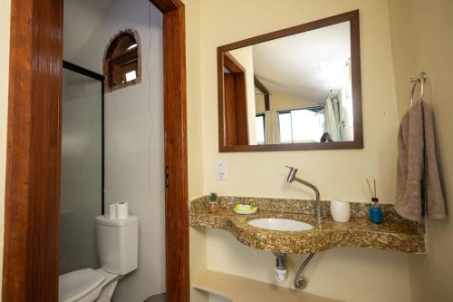 a bathroom with a sink and a mirror and a toilet at Suíte dos Reis in Angra dos Reis