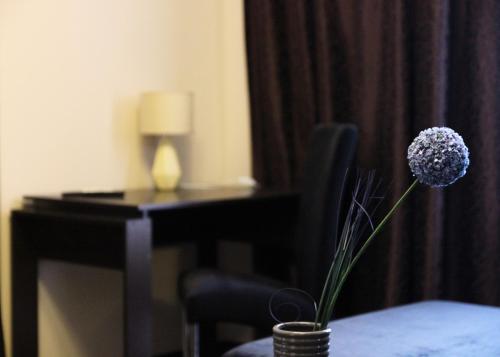 Alexandra Apartments Industrial Bridge في كييف: وردة في مزهرية على طاولة في غرفة الفندق