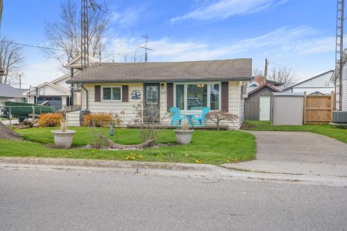 a house with a blue bench in the front yard at "At the Eau" - Charming 2 Bedroom Cottage! in Erieau