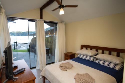 a bedroom with a bed and a tv and a window at Suíte dos Reis in Angra dos Reis