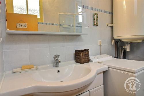 a white bathroom with a sink and a mirror at Les papillons in Plérin