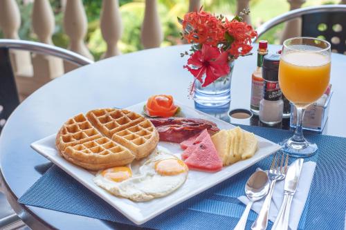 a plate of breakfast food and a glass of orange juice at Infinity Bay Spa & Beach Resort in West Bay