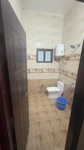 a bathroom with a toilet and a window and a door at Vanasiri stay inn in Sringeri