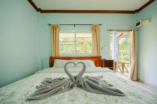 two swans are forming a heart on a bed at Baanklongkok in Ban Map Khangkhao