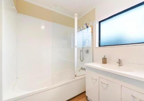 a white bathroom with a shower and a sink at Stylish Trentham Retreat in Upper Hutt