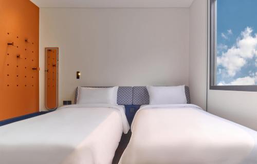 two beds in a room with a window at Go Hotel Khon Kaen Campas in Ban Nong Waeng