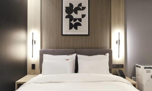 a bedroom with a bed with white sheets and pillows at Wonju Brown Dot Hotel Corporate city in Wonju