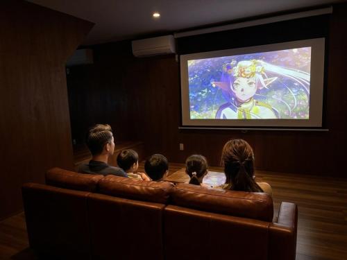 a group of people sitting on a couch watching a movie at Yoike Stay in Yonago