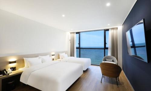 a bedroom with two white beds and a large window at Pohang Hound Hotel Songdo Beach in Pohang