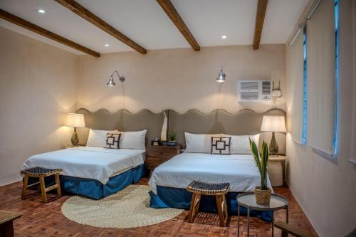 a bedroom with two beds and a table at Casa Katipunan in Manila