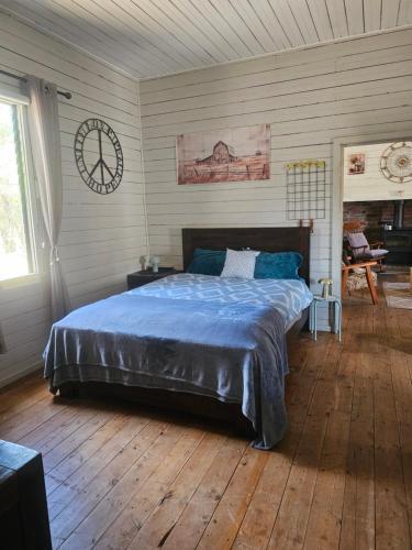 a bedroom with a bed and a clock on the wall at FarmStay Pepperina & Bird Sanctuary in Bendemeer