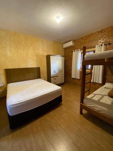 ein Schlafzimmer mit zwei Betten und einem Etagenbett in der Unterkunft Cantinho Rústico Brotas SP + Piscina Privativa + Ar Condicionado in Brotas