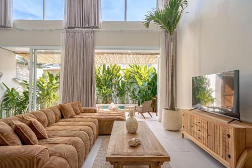 a living room with a large couch and a tv at Villa Pia Pererenan in Cemagi