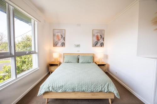 a bedroom with a bed and two windows at Aurora in Queenscliff