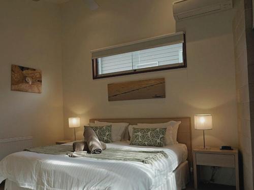a bedroom with a large white bed with a window at Beach Haven in Point Lonsdale