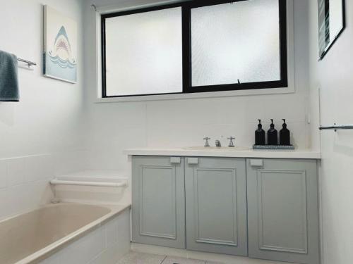 a bathroom with a sink and a tub and a window at Buckley s 10 in Point Lonsdale