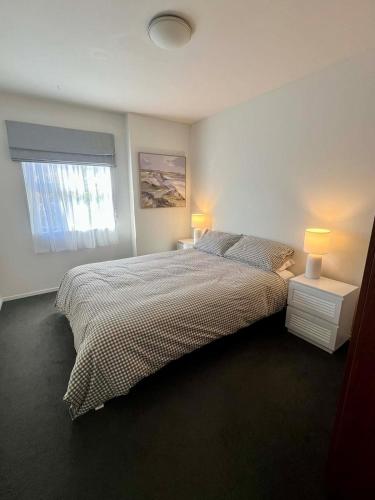 a bedroom with a bed with two lamps and a window at Wānaka Edge Retreat in Wanaka