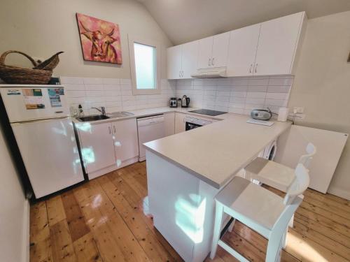 a kitchen with white cabinets and a white refrigerator at Doongarra in Queenscliff