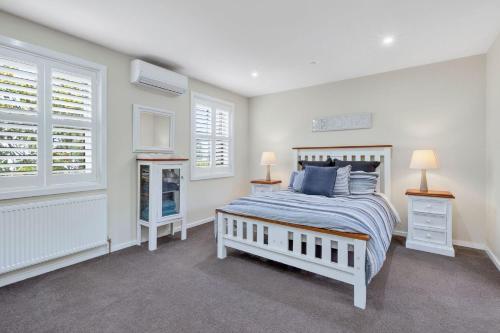 ein Schlafzimmer mit einem Bett, zwei Lampen und Fenstern in der Unterkunft Elenora in Queenscliff