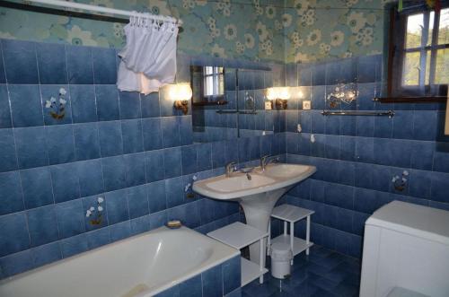 a blue tiled bathroom with a tub and a sink at La parrot en margeride in Pierrefiche
